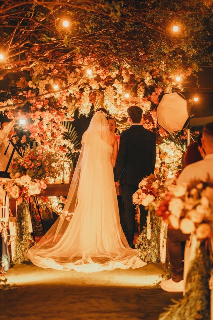 A beautifully illuminated outdoor wedding ceremony at night with bride and groom.