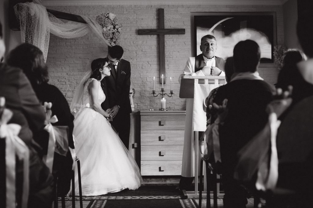 A romantic black and white photo of a wedding ceremony in a church setting.